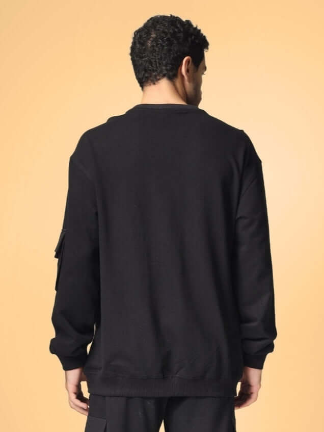 Back view of a model wearing a black oversized cotton terry sweatshirt showcasing premium heavy gauge fabric.