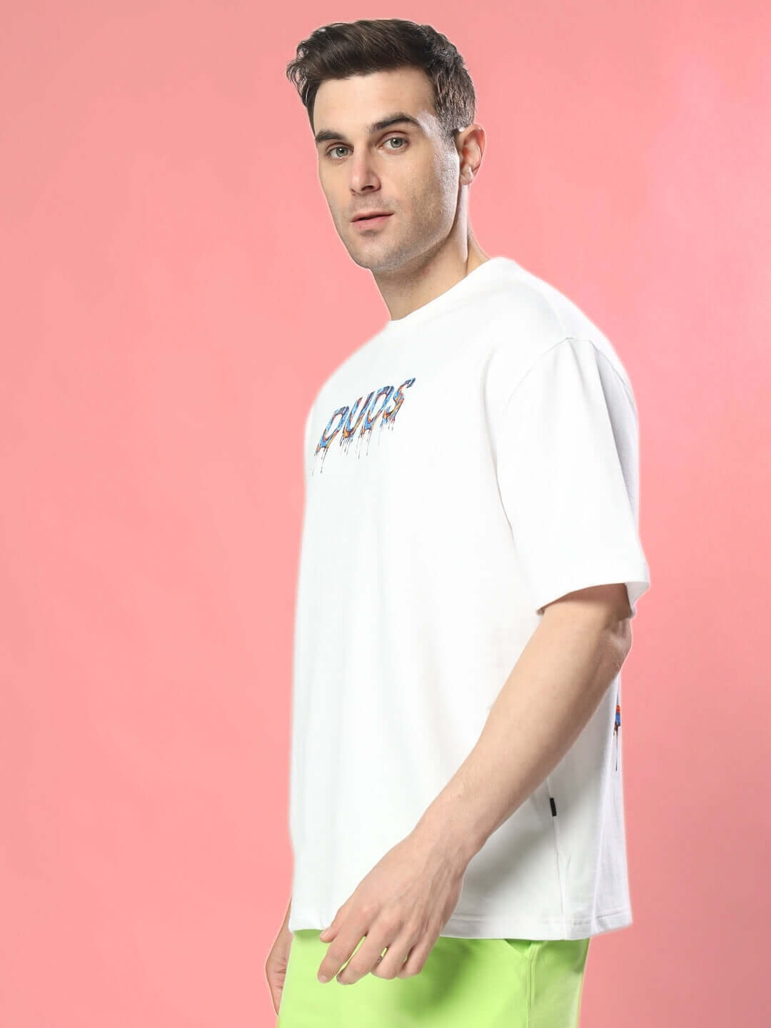 Person wearing MELTING EARTH OVER-SIZED T-SHIRT WHITE, featuring bold graphic, pink background.