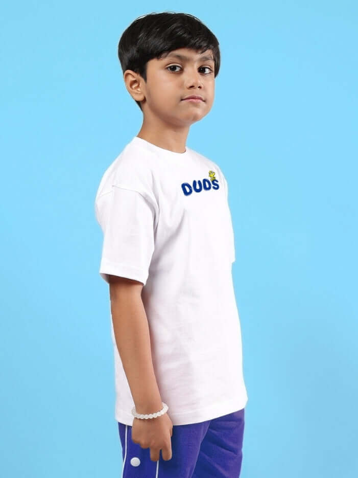 Child wearing BILLS COOL oversized white T-shirt for boys and girls by DUDS, standing against a blue background.