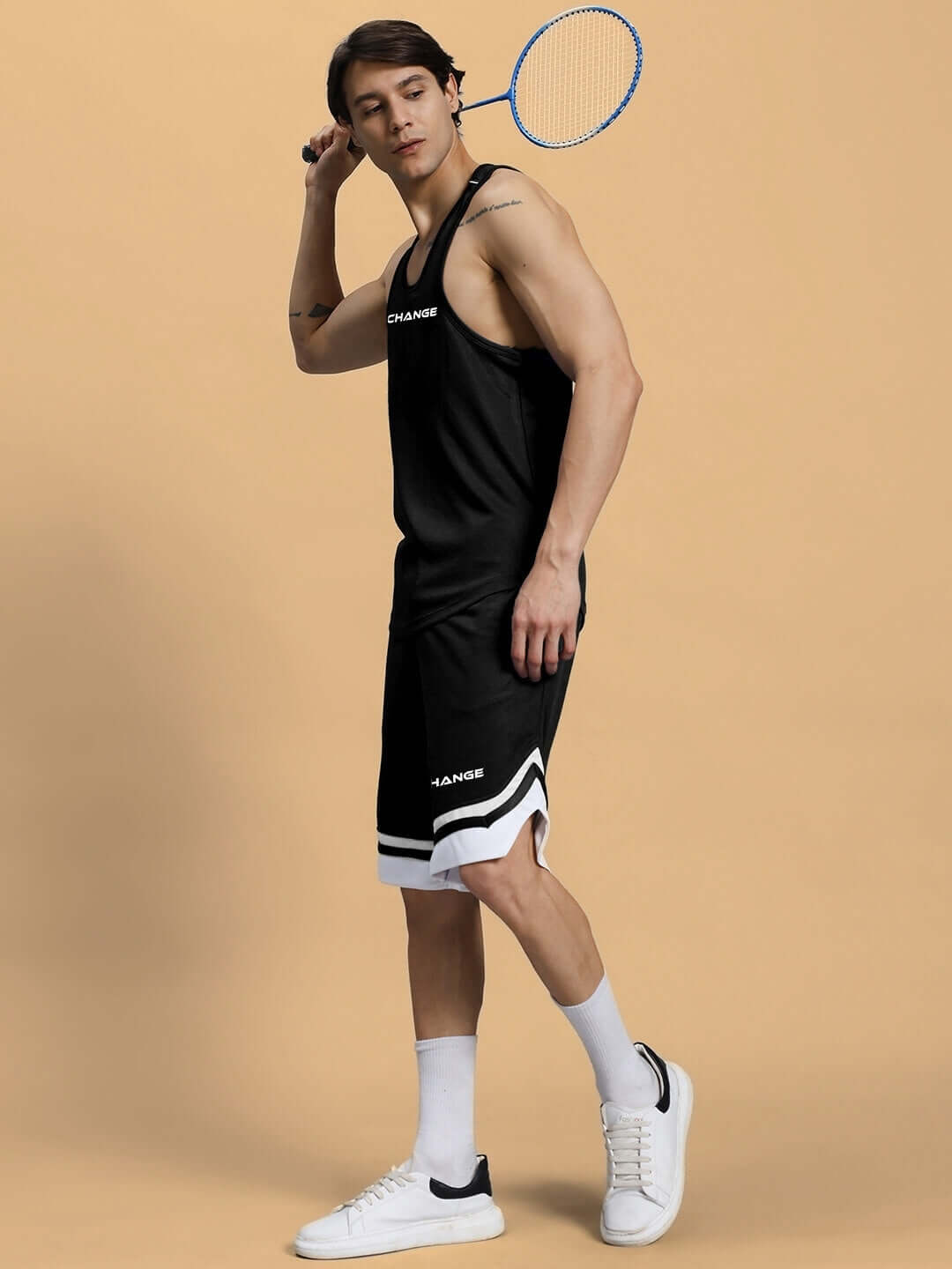 Model wearing Change Your Looks regular fit black shorts with a badminton racket, showcasing custom fit options for personalized style.