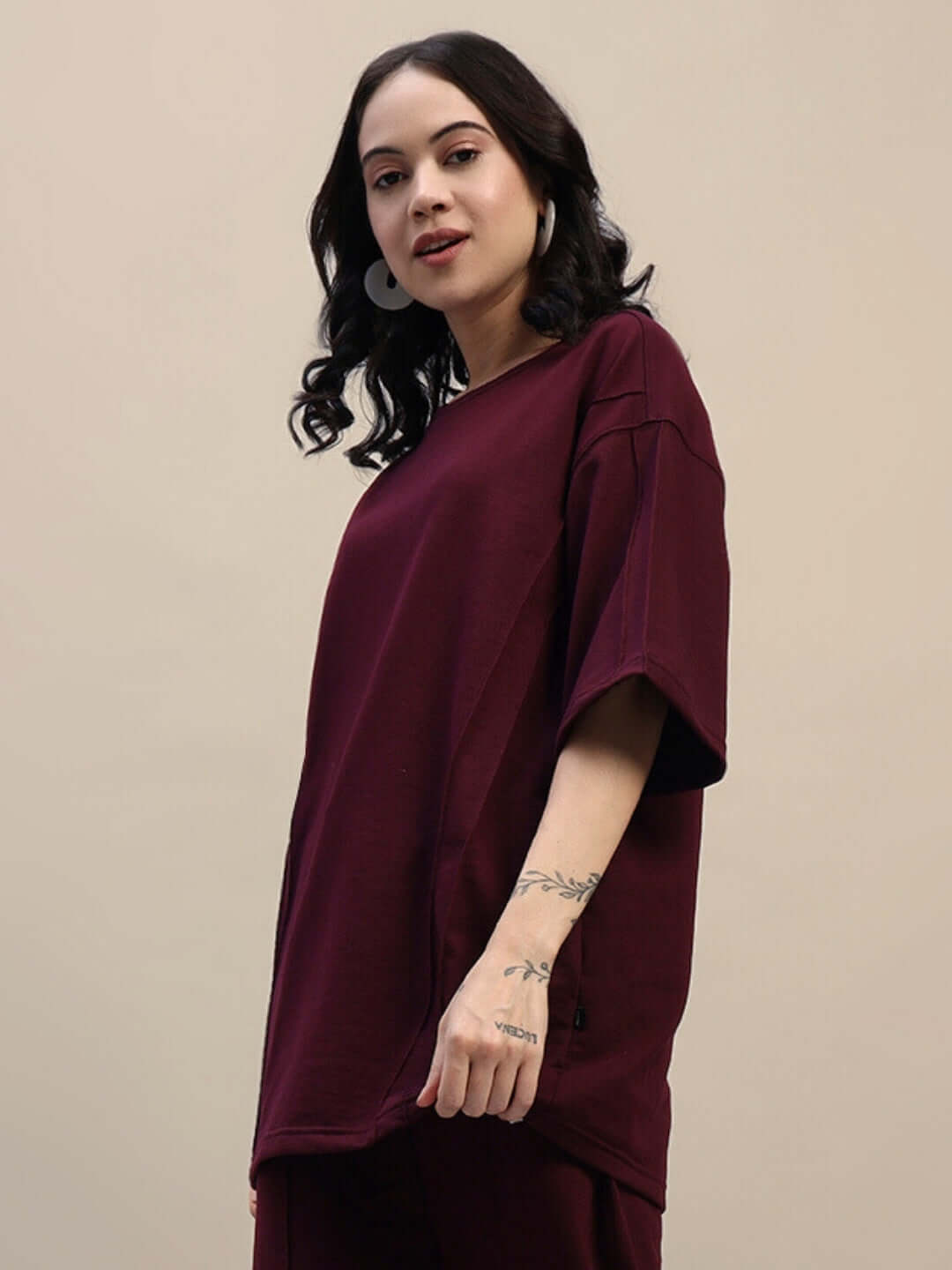 Woman wearing maroon oversized t-shirt made from premium heavy gauge fabric, showcasing relaxed fit and casual style.