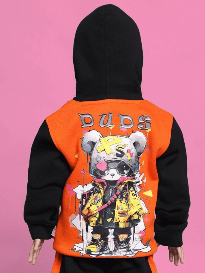 Graphic black-orange teddy co-ord with hood for boys and girls, featuring cool cartoon design on back, set against a pink background.
