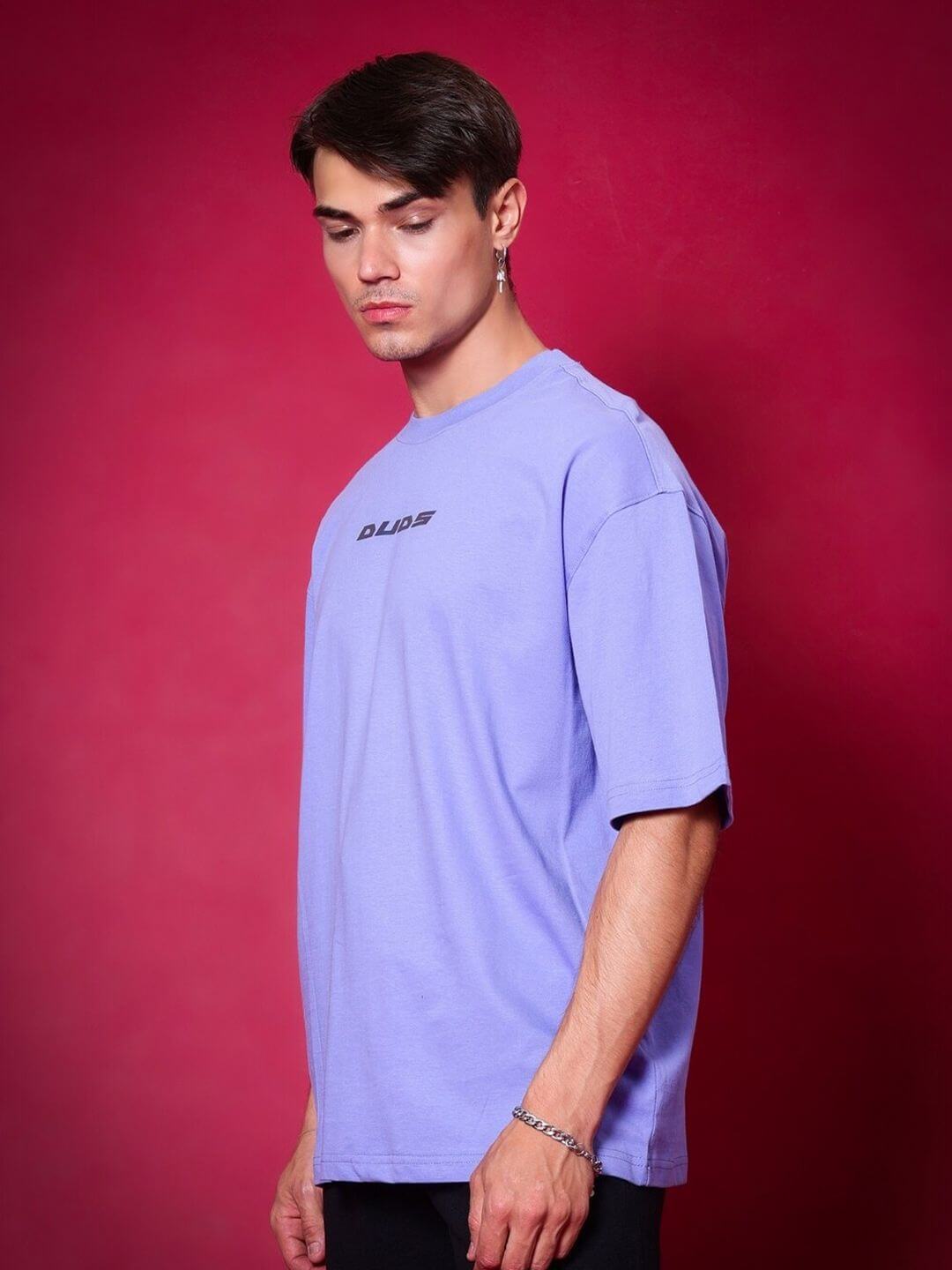 Alt Tag: Model wearing BREATHE OVER-SIZED T-SHIRT PERIWINKLE against a red background, showcasing DUDS brand style and fit options.