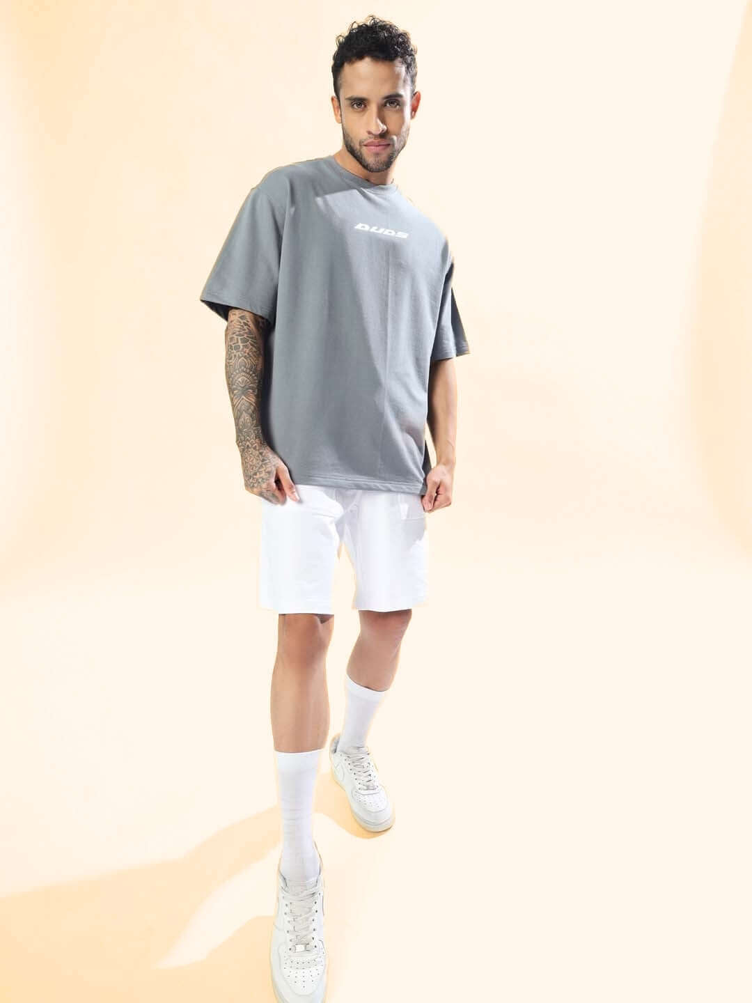 Model wearing the ONLY HOPE REMAINS OVER-SIZED T-SHIRT GREY with white shorts, showcasing a casual and comfortable streetwear style.