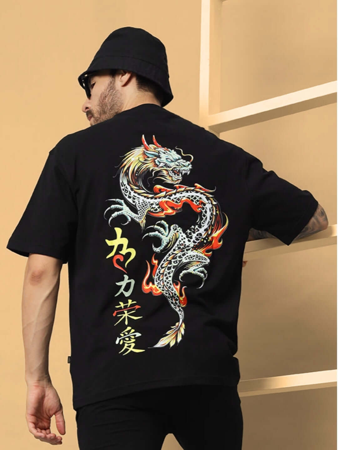 Man wearing KAKAAI OVER-SIZED T-SHIRT BLACK with dragon design on the back, available with Custom Fit option for prepaid orders.