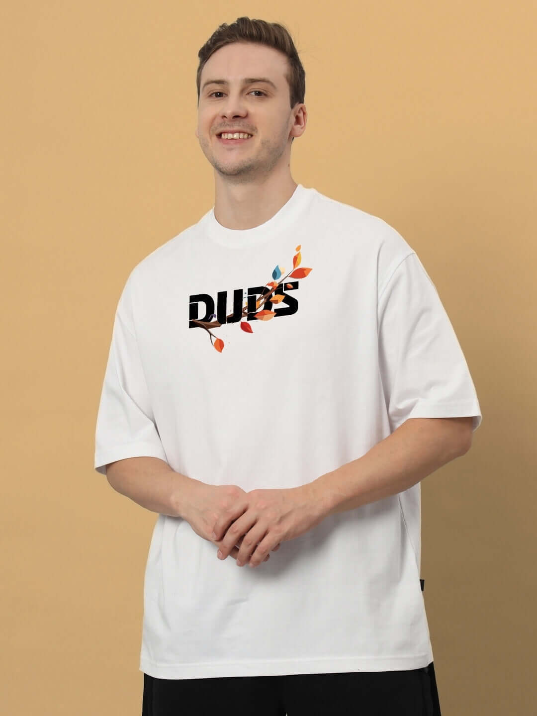 HEDWIG OVER-SIZED T-SHIRT WHITE with colorful leaf design, made from premium 100% cotton, worn by smiling model against beige background