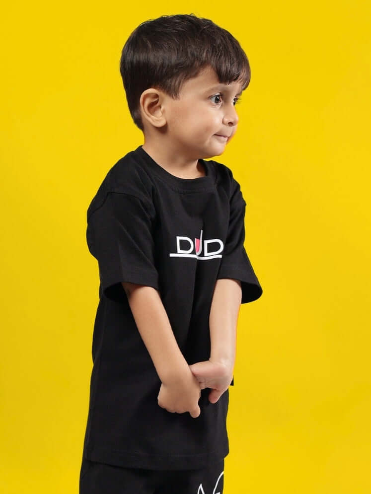 Boy wearing black Squid Battle T-shirt by DUDS against yellow background.
