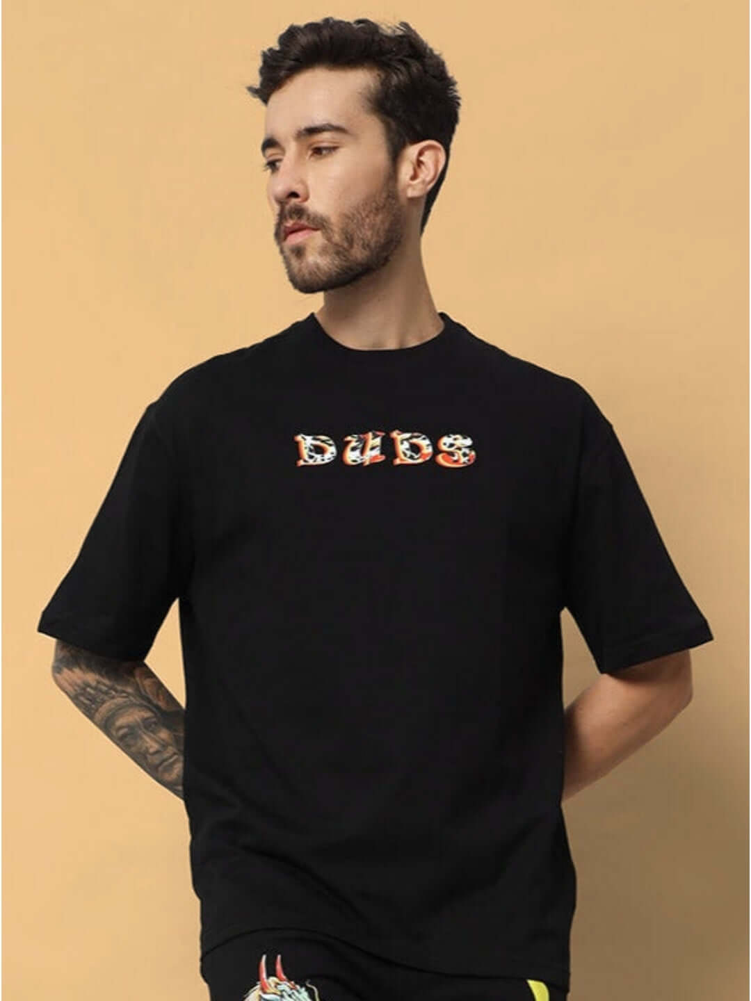 Man wearing KAKAAI OVER-SIZED T-SHIRT BLACK with DUDS logo