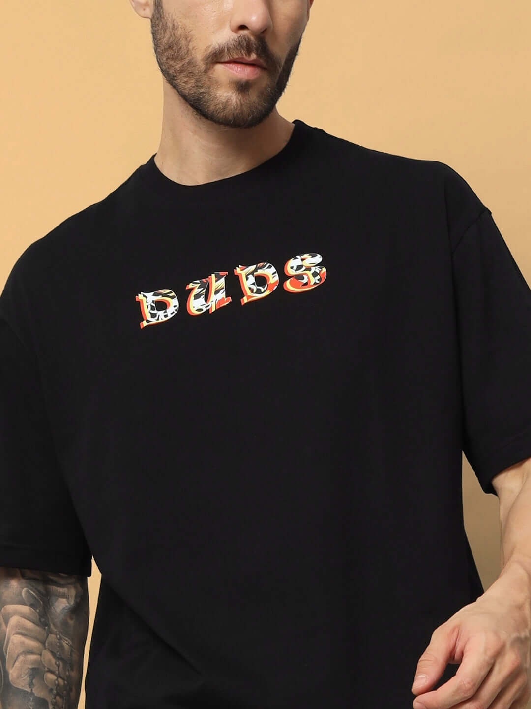 Man wearing KAKAAI OVER-SIZED T-SHIRT BLACK with DUDS logo on front