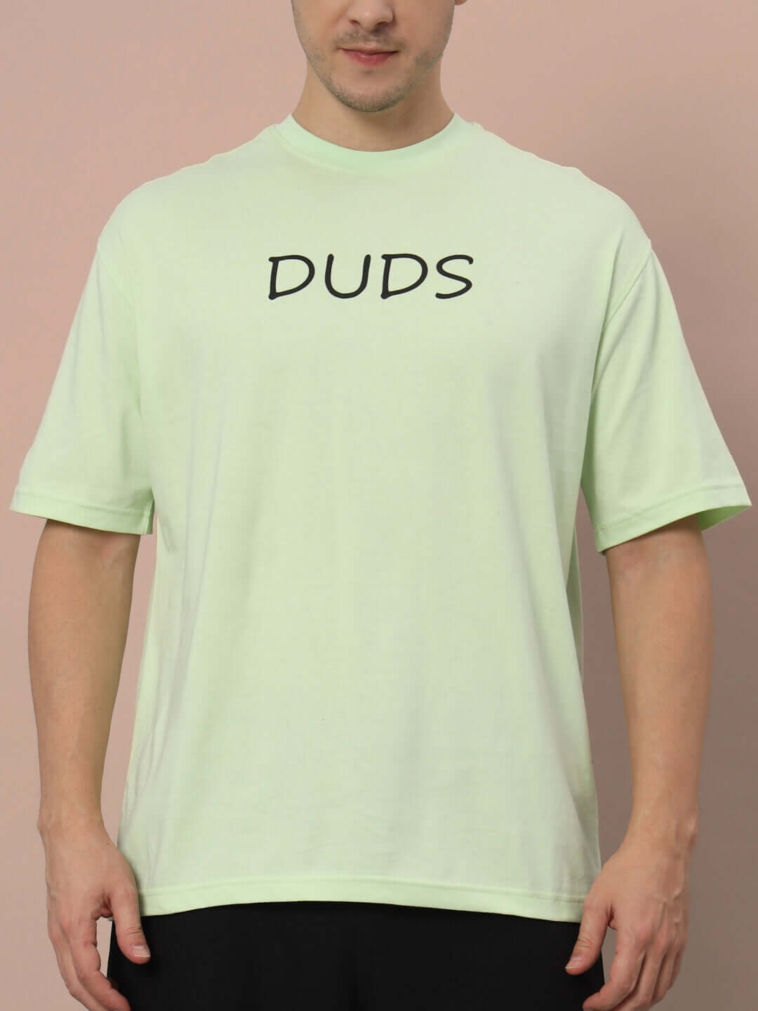 Model wearing DRINK JUICE OVER-SIZED T-SHIRT CELERY ICE in light green shade with bold logo.
