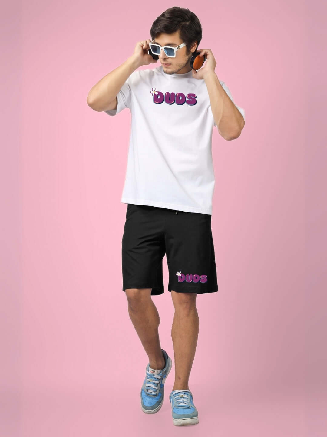 White and black summer co-ord set with graphic print, made from 97% cotton French Terry Lycra and 3% elastane. Model wearing sunglasses and headphones.