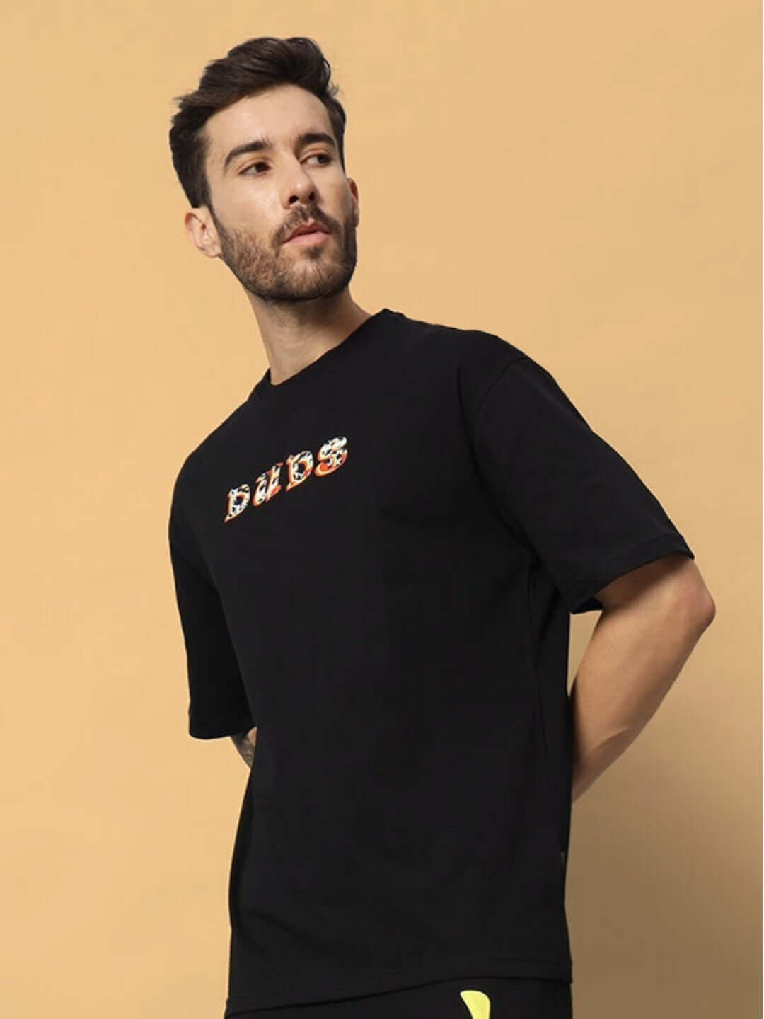 Model wearing KAKAAI OVER-SIZED T-SHIRT BLACK, featuring DUDS logo, suitable for custom fit options.