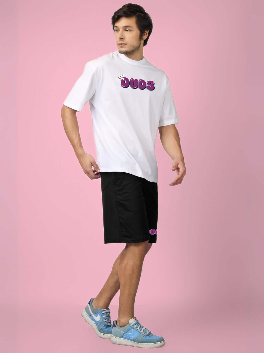 White and black summer co-ord set made of premium cotton French Terry Lycra, featuring a graphic top and shorts, modeled on pink backdrop.