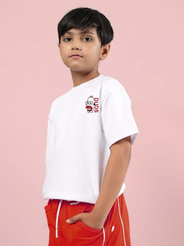 Child wearing a white Simpsons oversized t-shirt paired with red pants, posing against a pink background.