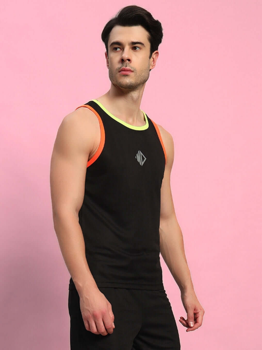 Man wearing a black Jordan gym t-shirt with colorful accents, standing against a pink background.
