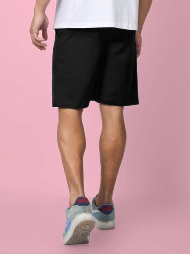 Person wearing black NO POS Summer Shorts, showcasing back view against a pink background for custom fit option.