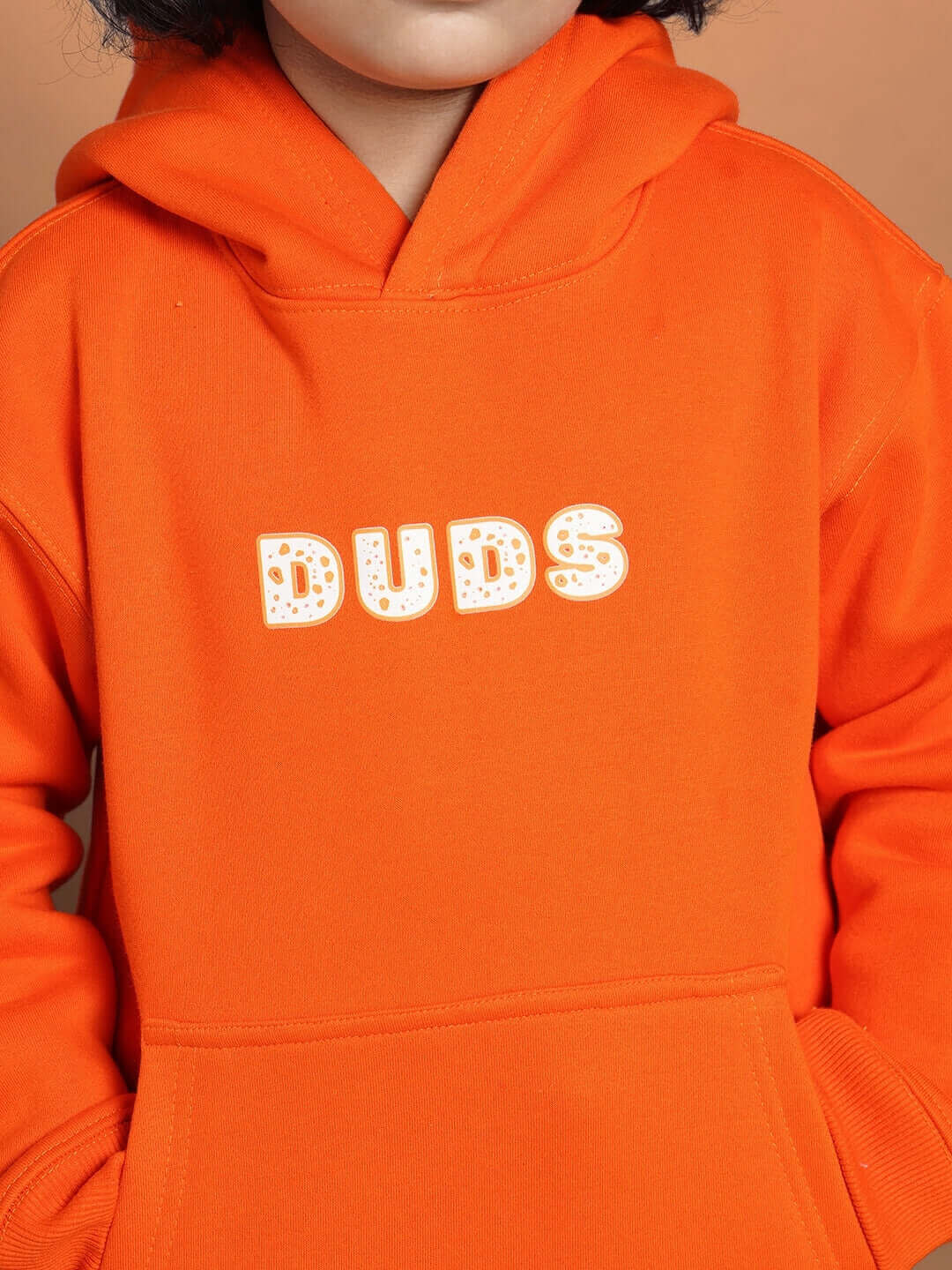 Child wearing orange hoodie with 'DUDS' text, part of the Courage Co-ord collection for boys and girls, front view.