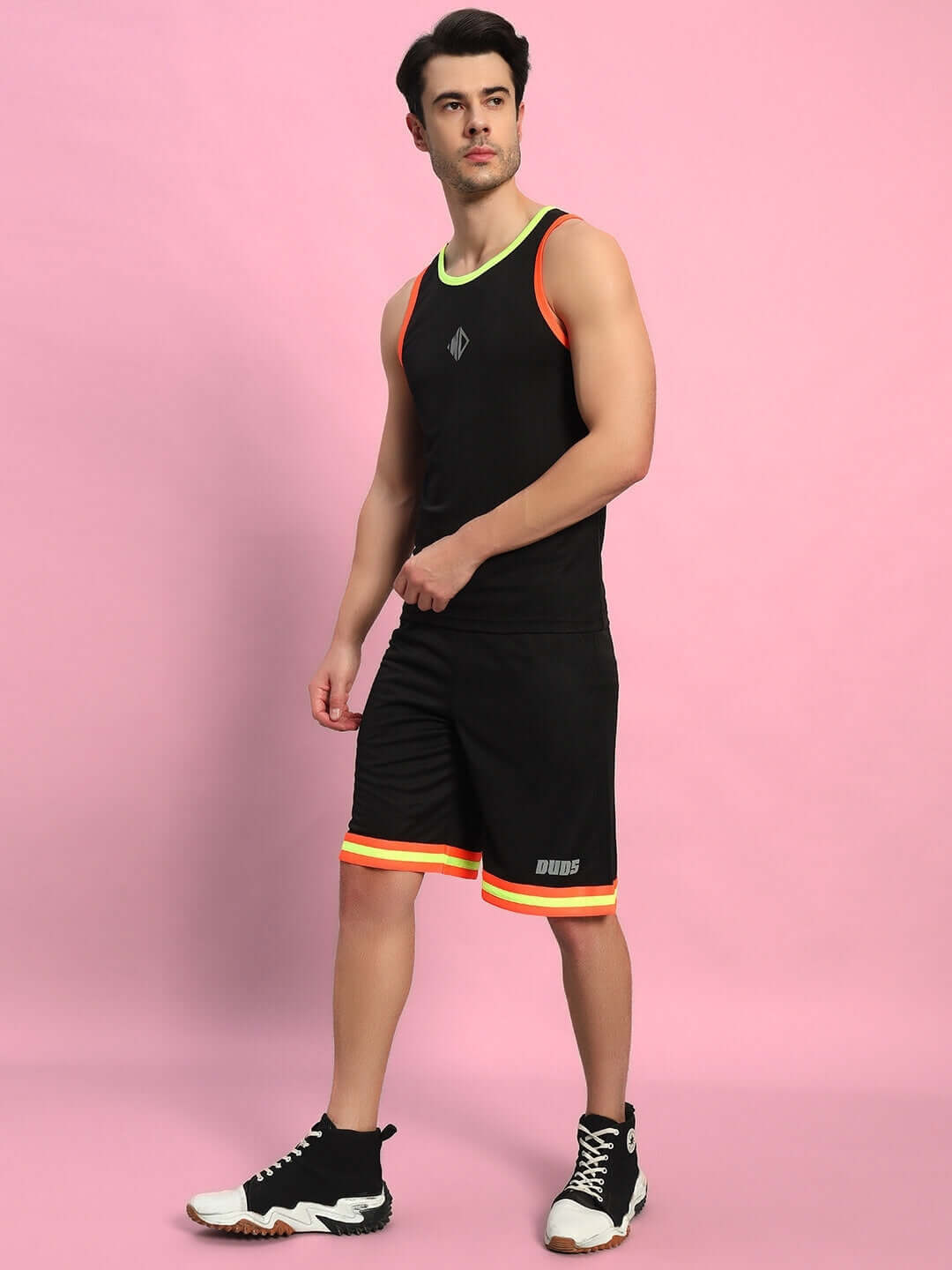 Man wearing a black Jordan gym co-ord set made of sports polyester fabric, standing against a pink background in athletic sneakers.