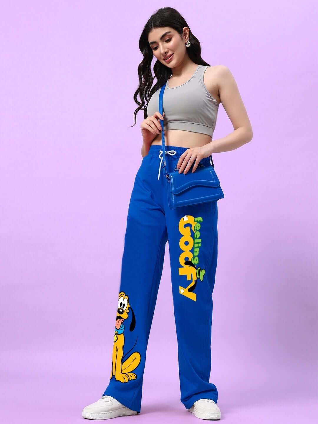 Woman wearing blue relaxed fit joggers with Feeling Goofy print, paired with a gray crop top, showcasing casual style and comfort.