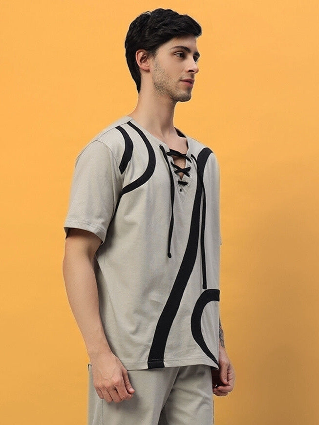 Man wearing a grey surfing designer oversized T-shirt with abstract black patterns, crafted from premium cotton and elastane blend.