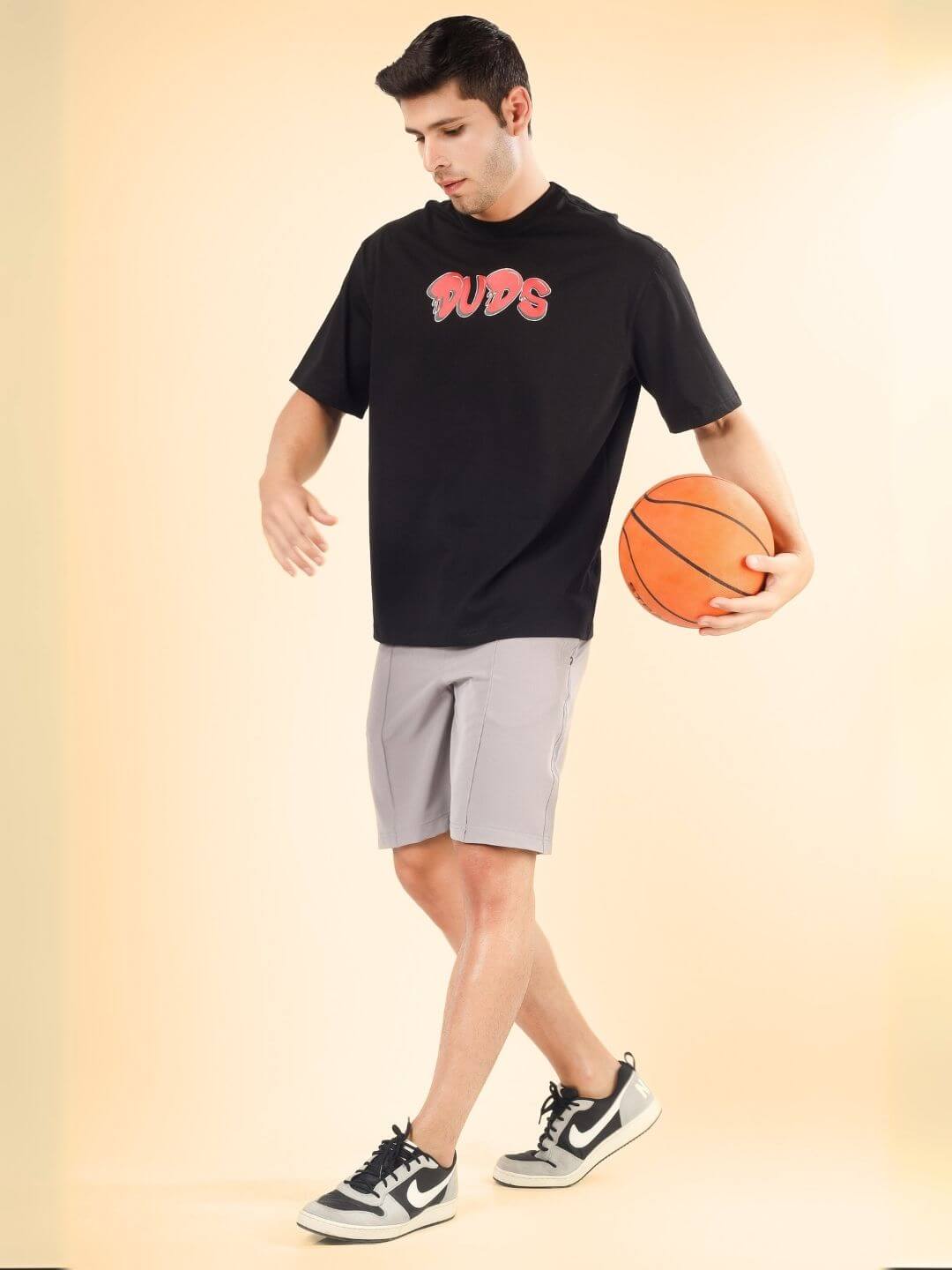 Model wearing DRIP 2 HARD OVER-SIZED T-SHIRT BLACK, holding a basketball.
