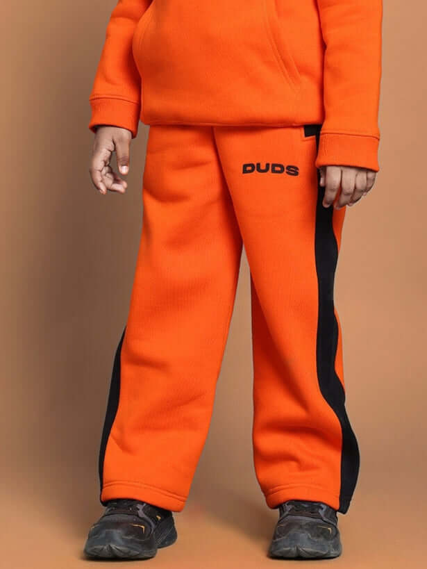 Child wearing orange Courage fleece pants with black side stripes, ideal for boys and girls. Comfortable winter wear.
