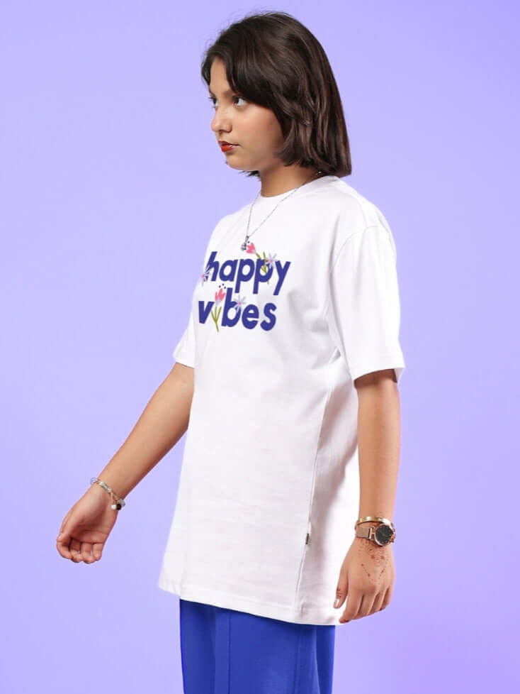 Child wearing white 'Happy Vibes' T-shirt, suitable for boys and girls, against a purple background.