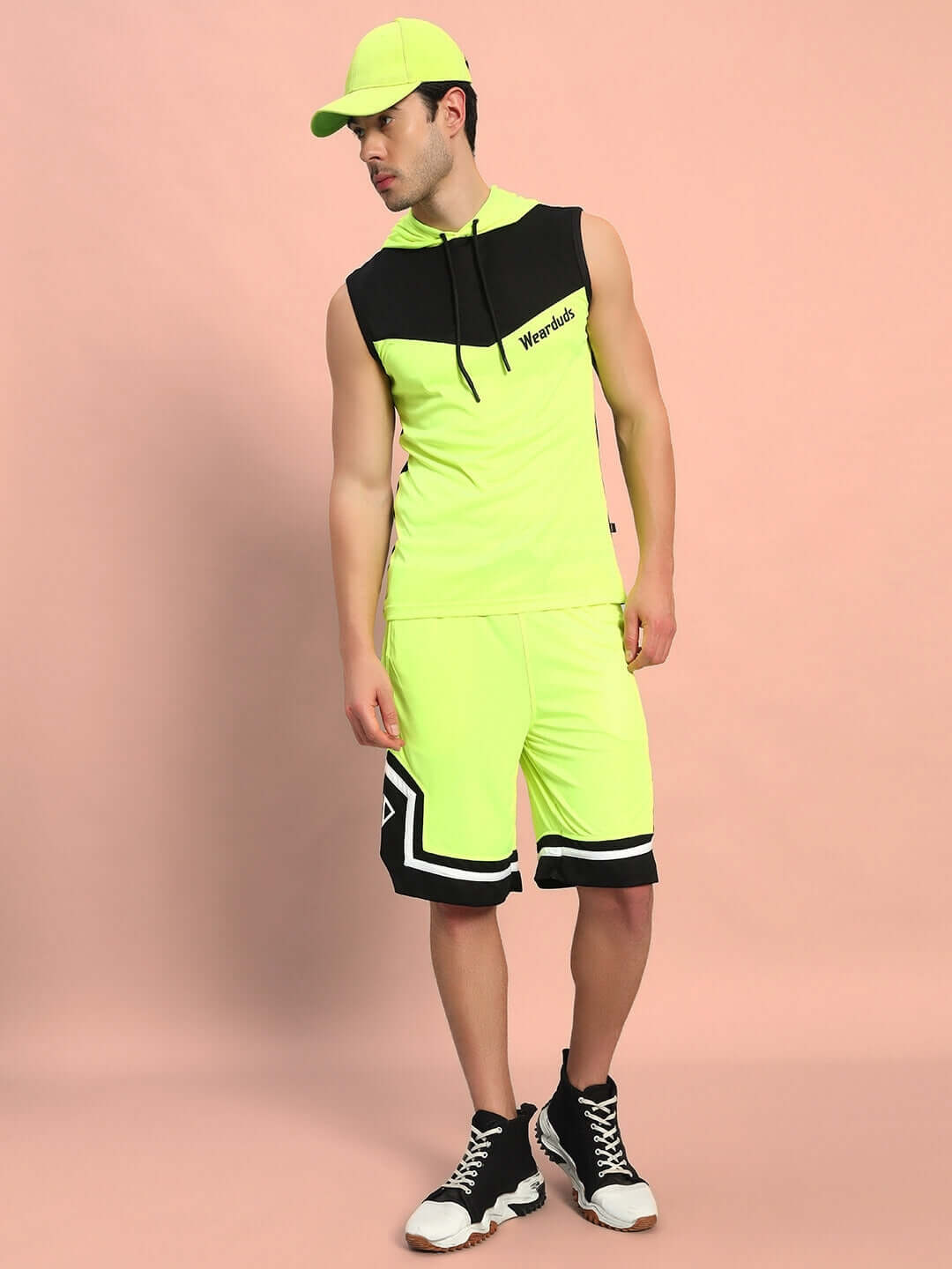 Model wearing ARMADO regular fit neon green shorts with matching cap, showcasing casual sportswear style.
