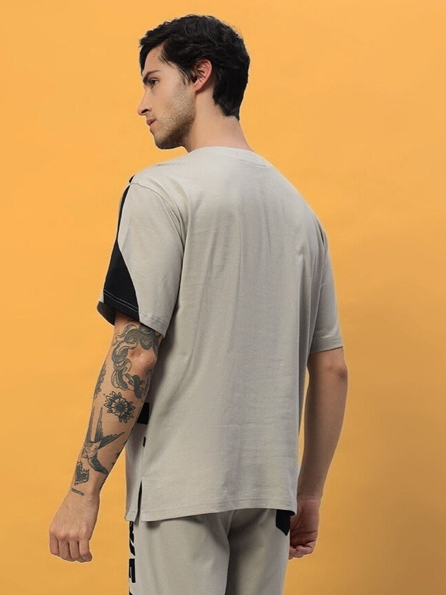 Rear view of man wearing a grey oversized surfing designer t-shirt with black accents, showcasing premium fabric and stylish design.