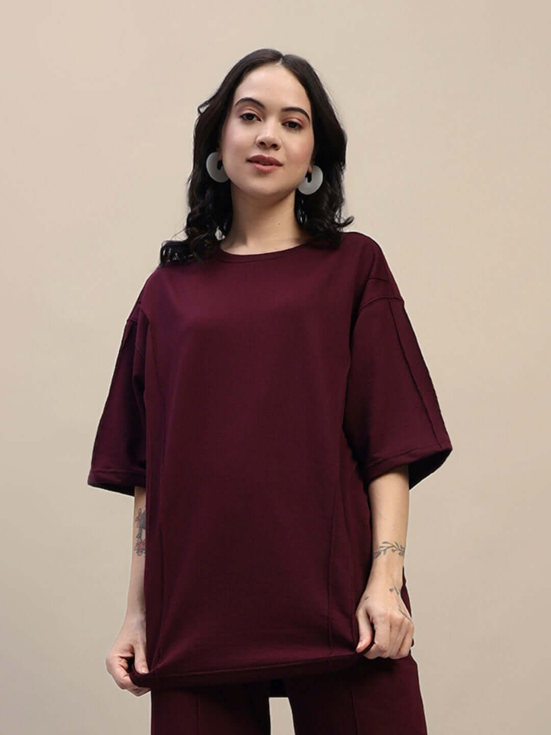 Woman wearing maroon oversized t-shirt made from premium cotton French terry lycra, highlighting relaxed fit and casual style.