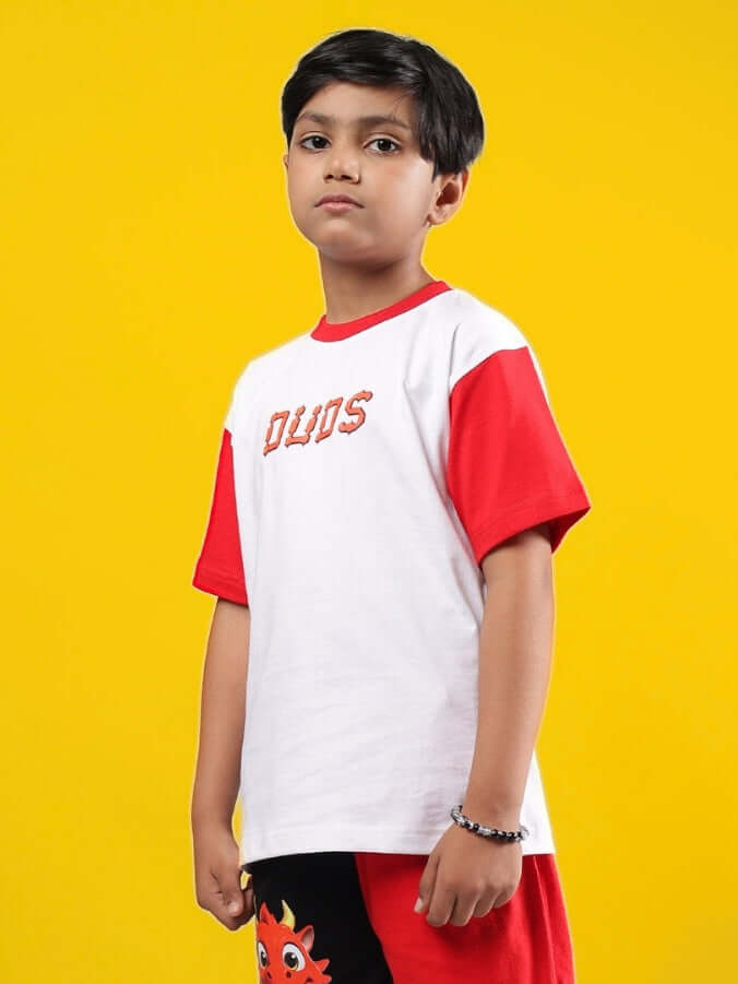 Child wearing a DUDS white and red Cassie t-shirt, showcasing unisex fashion for boys and girls, against a yellow background.