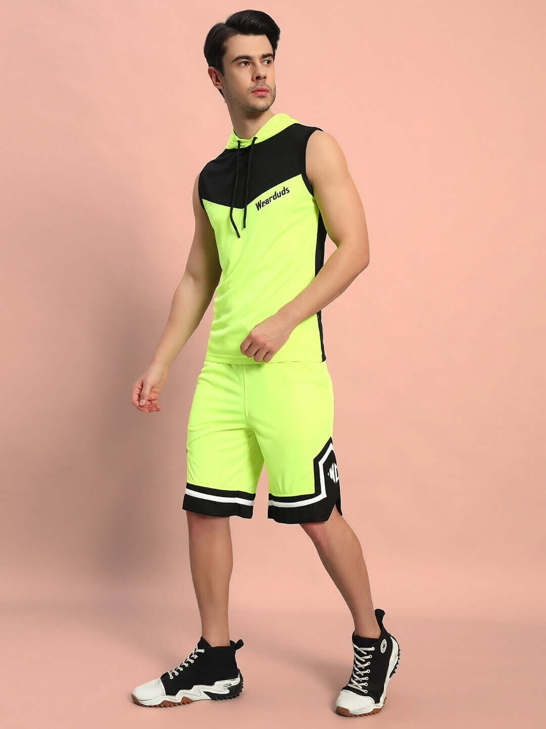 Neon green FRANKY GYM CO-ORD SET made from sports polyester, featuring sleeveless top and shorts. Ideal for workouts. Model posing on peach background.