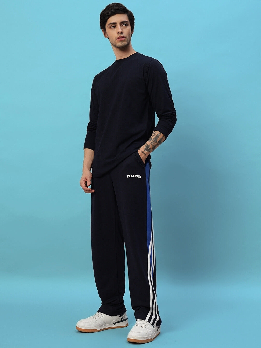 Model wearing navy blue TANGLE relaxed-fit joggers from DUDS, showcasing a casual style. Perfect for comfort and custom size options.
