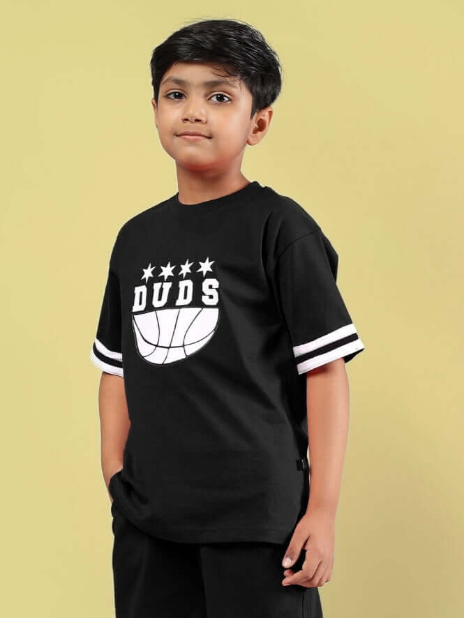 Young boy wearing black Diggin oversized t-shirt with DUDS logo and white stripes, casual and stylish clothing for kids.