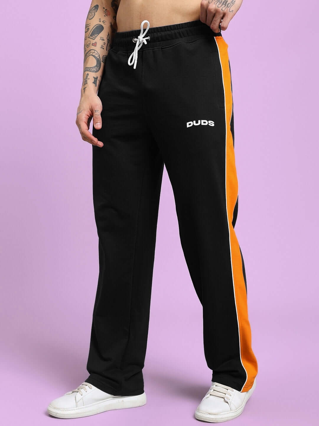 Person wearing black joggers with a bright orange stripe, featuring "DUDS" branding, perfect for comfort and style in casual wear.