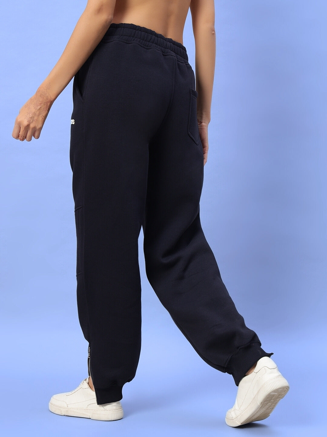 Back view of navy blue women's fleece pants, part of a Fight Night Co-Ord, styled with white sneakers against a light blue background.