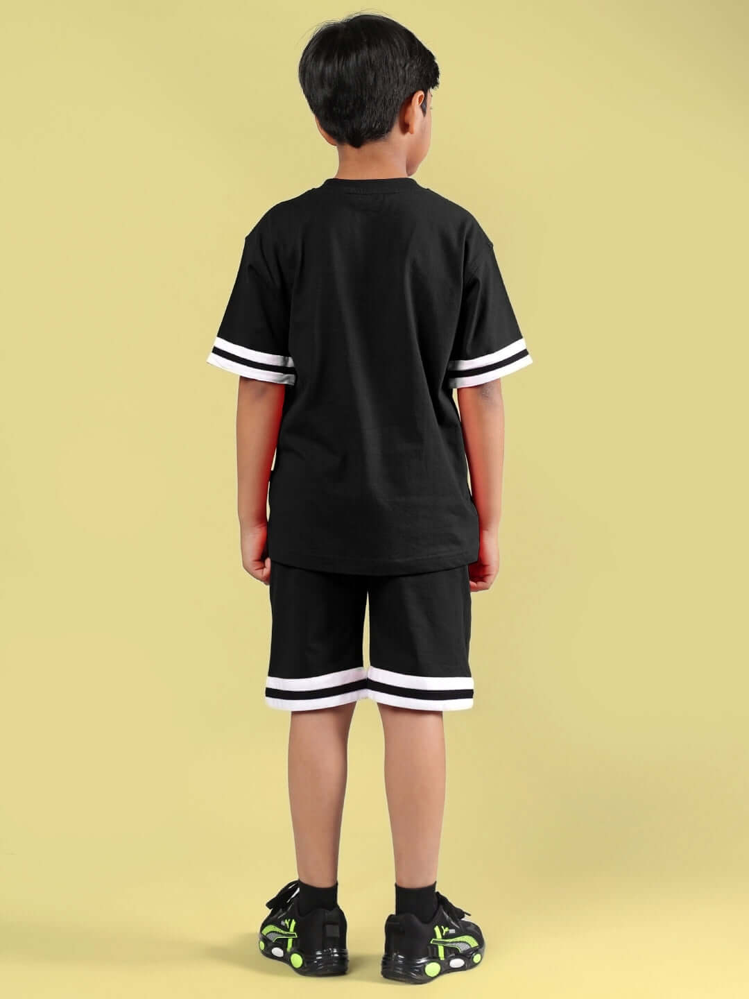 Young boy wearing black Diggin Co-ord by DUDS, shown from back, featuring shorts and t-shirt with white accents, ideal for boys and girls.
