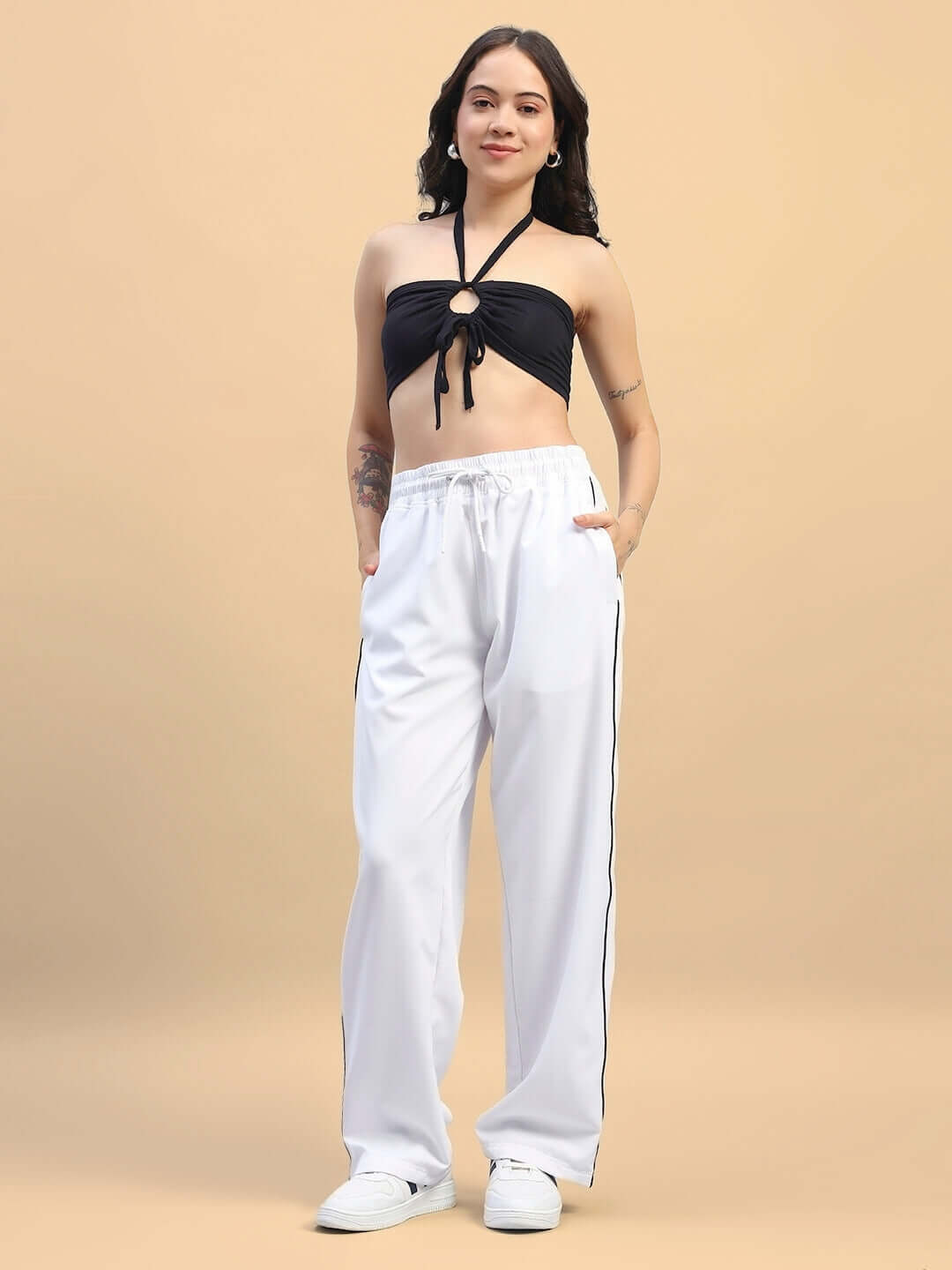 Woman wearing women's white relaxed-fit joggers with customizable size option and a black top, standing against a beige background.