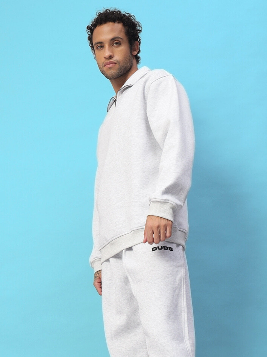 Man wearing BONA-FIDE sweatshirt in melange grey against a blue background