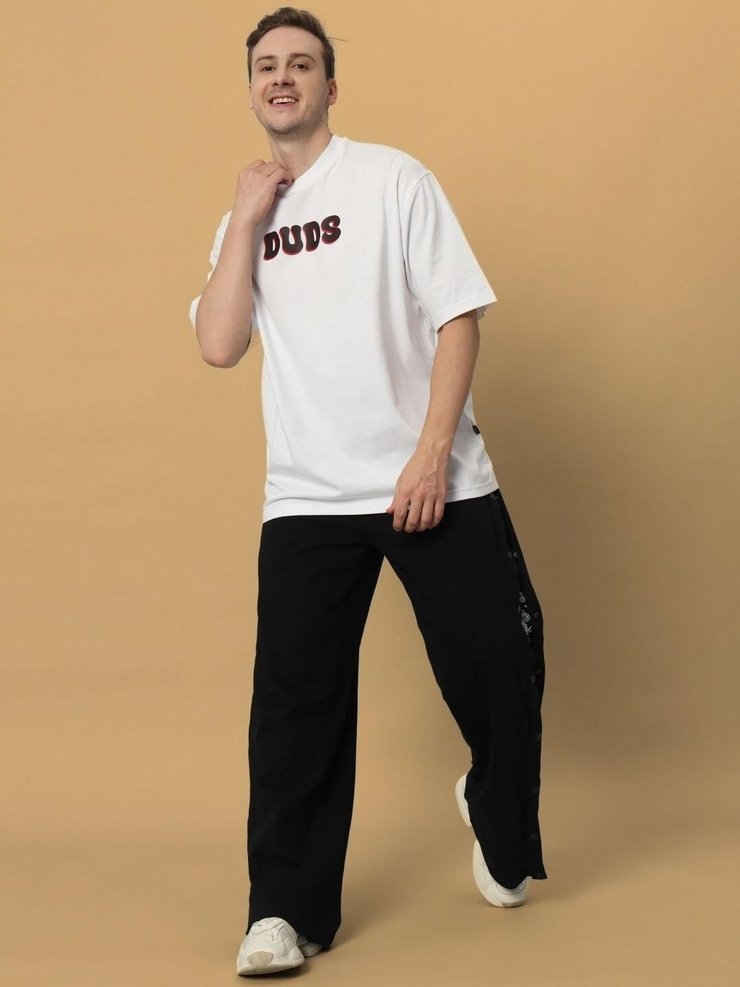 Model wearing CARINO OVER-SIZED T-SHIRT WHITE with black pants, showcasing casual style.