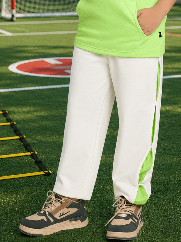 CURIOUS JOGGER FOR BOYS GIRLS OFF WHITE worn by a child in green attire on a sports field.
