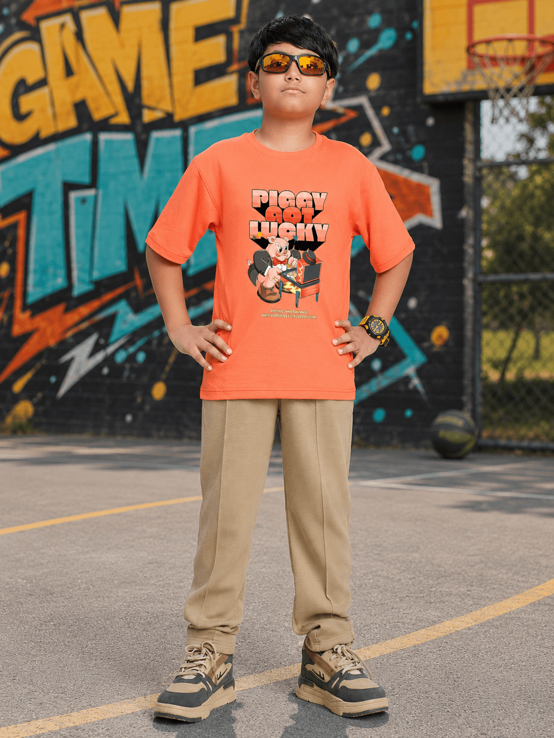 Boy wearing orange t-shirt and beige joggers, showcasing COMIC STREET JOGGER FOR BOYS GIRLS BEIGE in a playful setting.