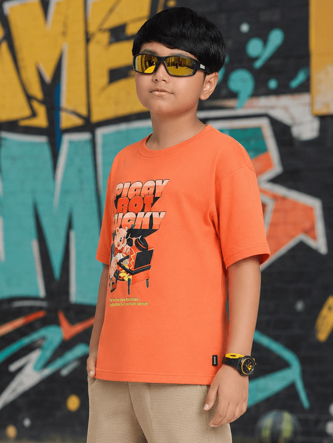 Boy wearing a COMIC STREET T-SHIRT FOR BOYS GIRLS ORANGE with sunglasses in front of colorful graffiti.
