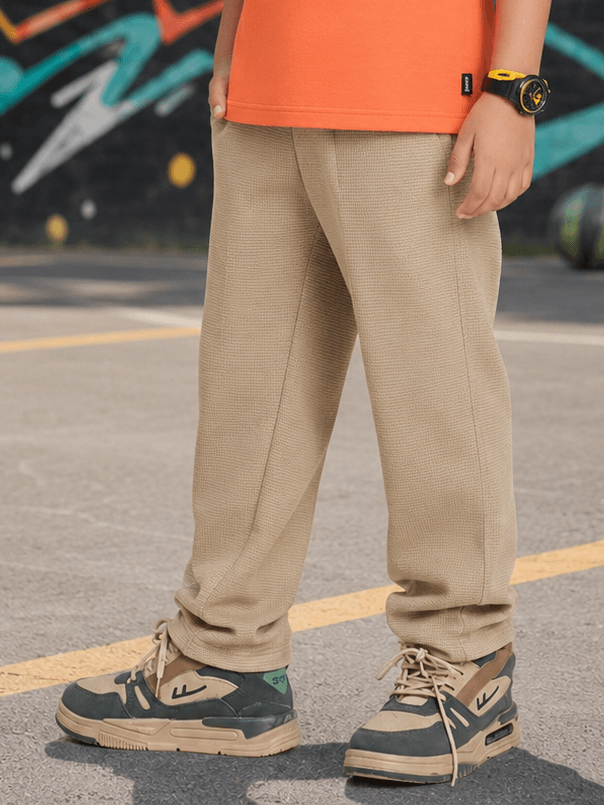 COMIC STREET JOGGER FOR BOYS GIRLS BEIGE worn by a kid, featuring beige joggers and stylish sneakers.