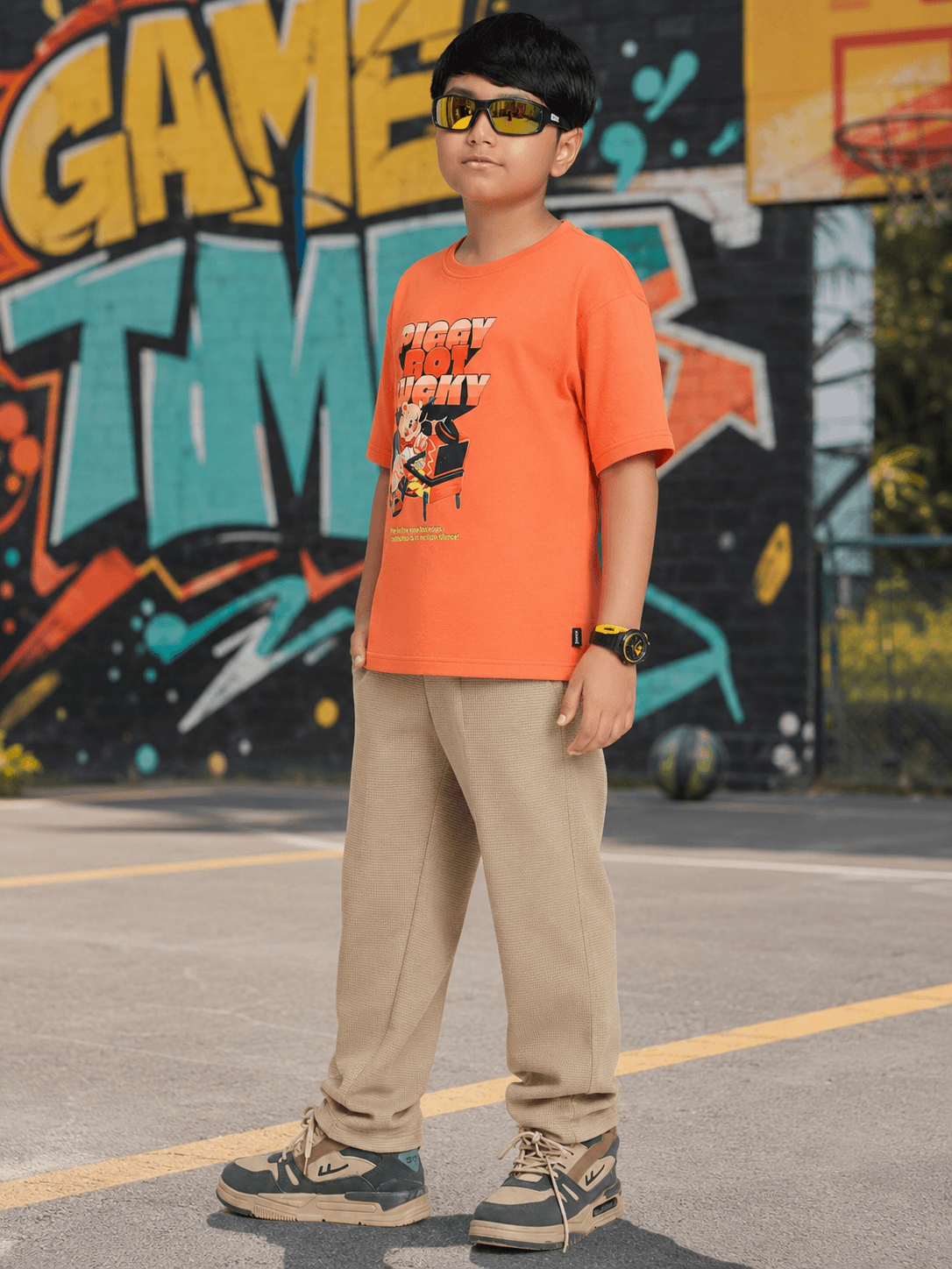 COMIC STREET GRAPHIC CO-ORD FOR BOYS GIRLS ORANGE BEIGE modeled by a kid in urban setting with sunglasses.