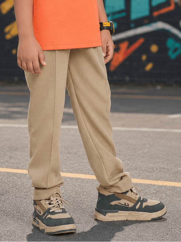 COMIC STREET JOGGER FOR BOYS GIRLS BEIGE showcased in a casual outdoor setting with trendy sneakers.