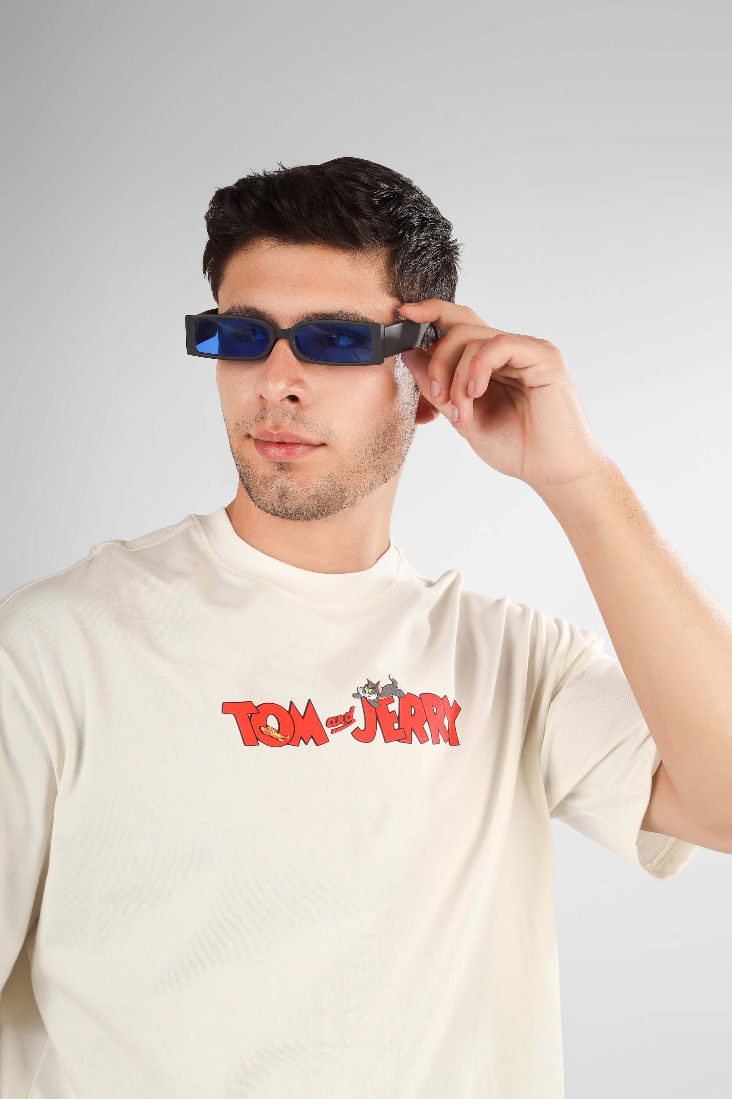 Person wearing TOM & JERRY OVER-SIZED T-SHIRT CREAM and blue sunglasses.