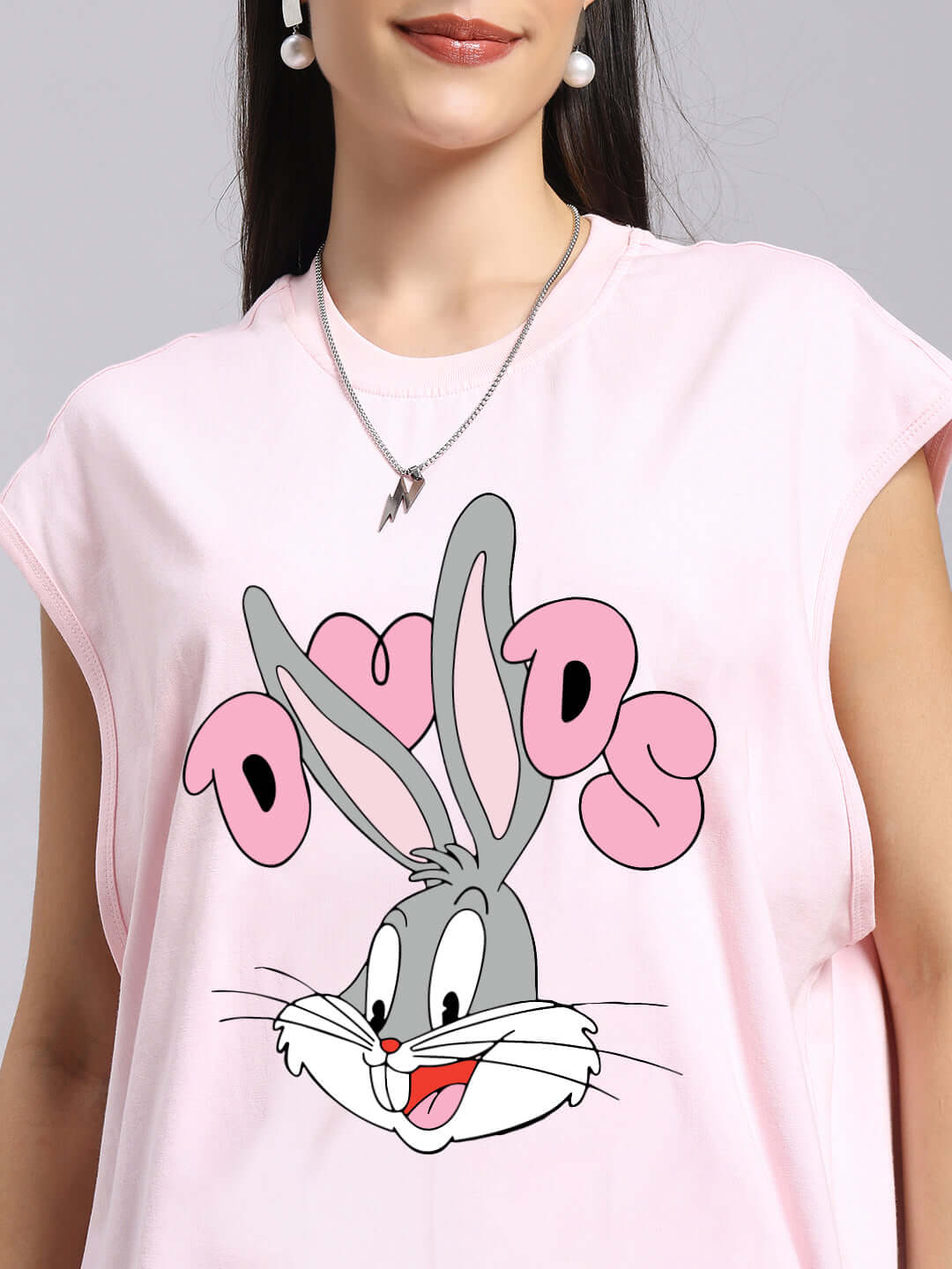 Woman wearing a pink T-shirt featuring a cool bunny print with 'DUDS' text, showcasing a stylish casual look.