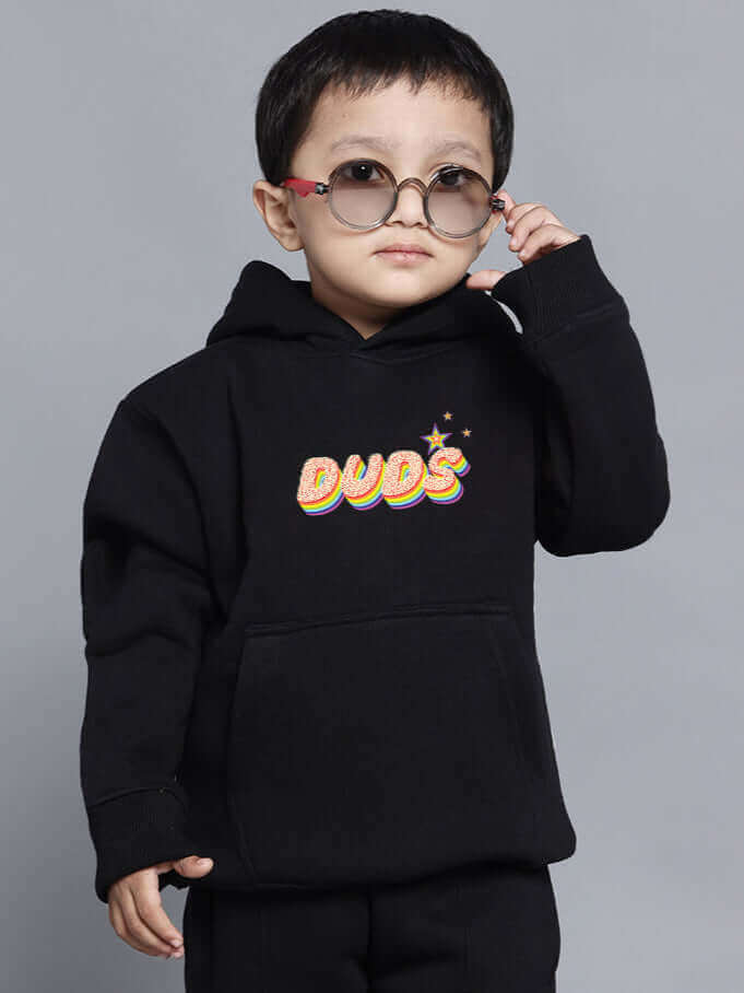 Child wearing black BORN TO SHINE co-ord hoodie for boys and girls, featuring "DUDS" graphic, and stylish sunglasses.