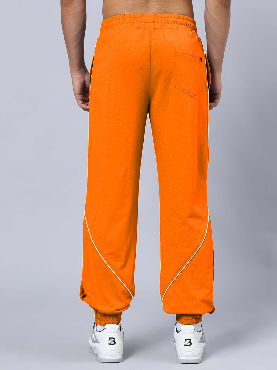 Back view of orange cotton relaxed fit joggers with elasticated waistband and drawstring detail.